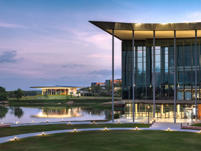 VISTEC academic building and Learning Center reflected in the campus lake at dusk