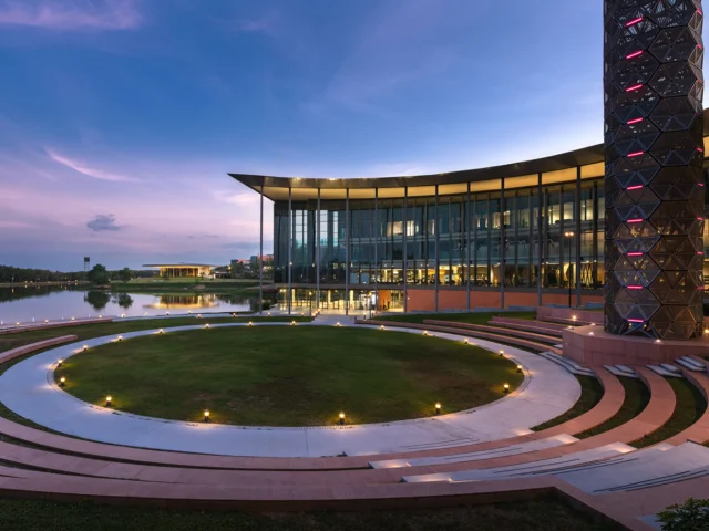 VISTEC Learning Center building lit up at dusk beside the campus lake